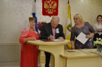 пожилые мужчина и женщина в фате в ЗАГСЕ женщина регистратор флаг герб России