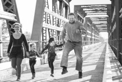 мужчина женщина мальчик и девочка радостные бегут по мосту